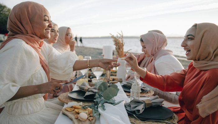 women in hijab having picnic on the beach