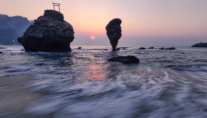 cliffs in sea near coast at sunset