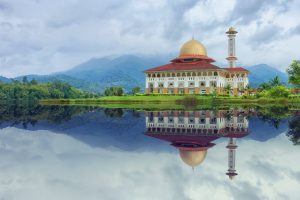 white and red house reflecting on body of water under blue sky