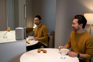 smiling man sitting by the table with a bowl of soup and glass of water