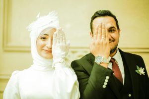 smiling newlyweds with hands over faces