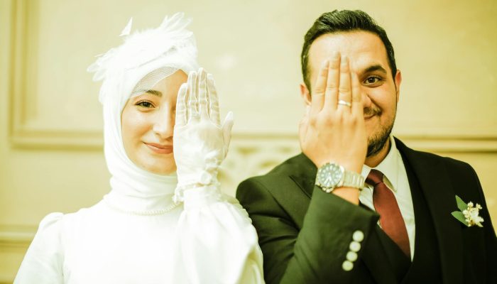 smiling newlyweds with hands over faces